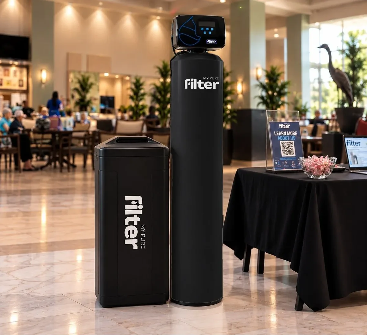 A My Pure Filter whole-house water filtration tank and brine tank on a polished floor in a bright public lobby.